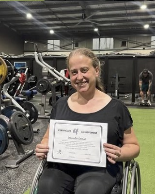 Danielle holding her certificate of achievement in the gym