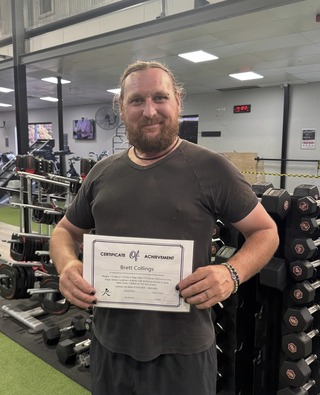 Bret holding his certificate of achievement in the gym